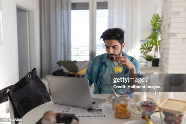 young muslim man having home-office at dining table in his flat during breakfast. - middle east food stock pictures, royalty-free photos & images