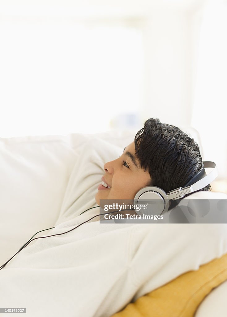 USA, New Jersey, Jersey City, Boy (12-13) listening music on sofa