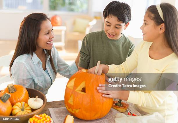 usa, new jersey, jersey city, mother with son (12-13) and daughter (10-11) doing jack o lantern - jersey city stock pictures, royalty-free photos & images