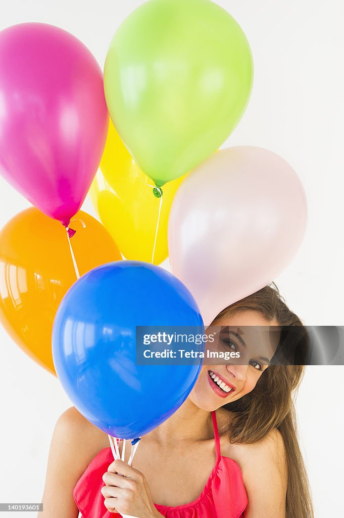 Smiling woman holding balloons, studio shot