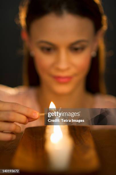 woman igniting candle - candle photos et images de collection