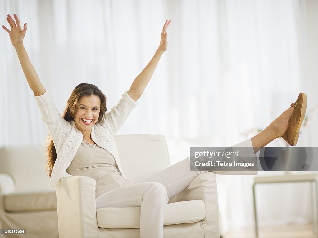 USA, New Jersey, Jersey City, Excited woman sitting in chair at home