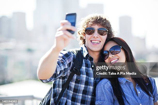 usa, washington, seattle, couple wearing sunglasses photographing themselves with smart phone -  "suprijono suharjoto" or "take a pix media" stock pictures, royalty-free photos & images