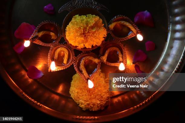 lit brass oil lamp and marigold flowers in a copper plate/happy diwali - diya oil lamp stockfoto's en -beelden