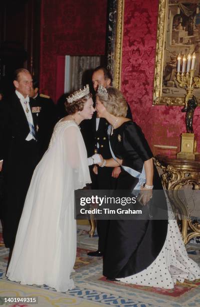 Queen Elizabeth greets Queen Sofia with a kiss at a State Banquet held at El Pardo Palace in Madrid, Spain, 17th October 1988.