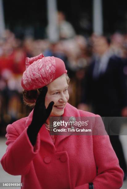 Queen Elizabeth wearing a pair of gloves by Cornella James and a pink outfit, smiles and waves to the crowd in Madrid, Spain, 18th October 1988.