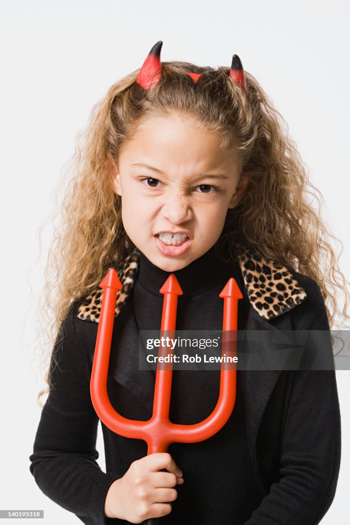 Girl (8-9) posing wearing devil costume, studio shot