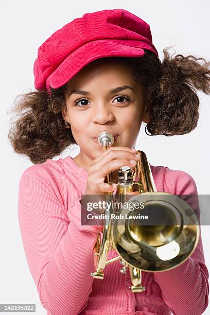 portrait of girl (8-9) playing trumpet, studio shot - trumpet stockfoto's en -beelden