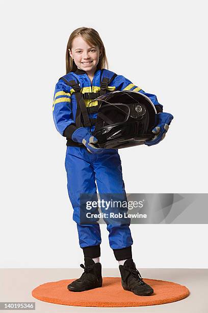 portrait of girl (8-9) dressed as racing driver, studio shot - coureur automobile photos et images de collection