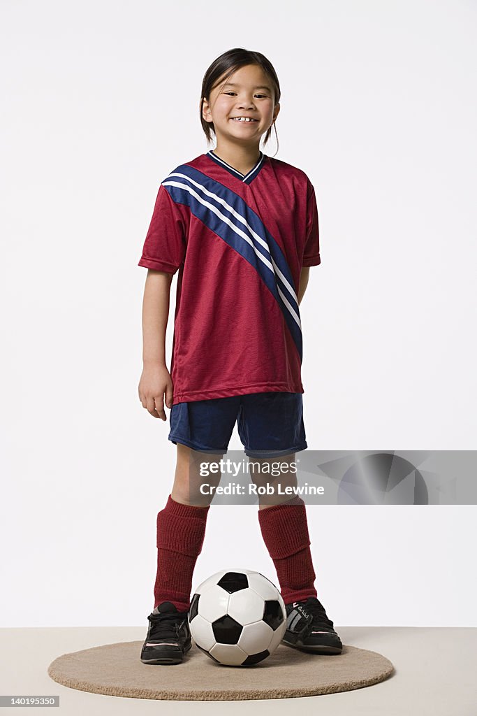 Smiling girl (8-9) wearing soccer uniform, studio shot