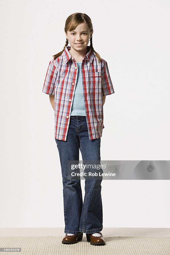 Portrait of smiling girl (8-9) wearing checked shirt, studio shot