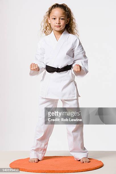 studio portrait of smiling girl (8-9) wearing gi - karate girl stock-fotos und bilder
