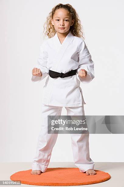 studio portrait of smiling girl (8-9) wearing gi - karate girl stockfoto's en -beelden