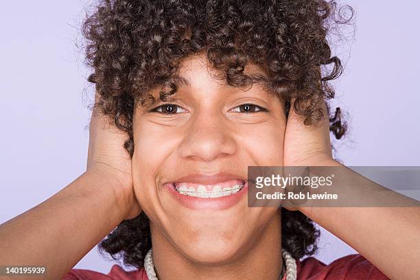 portrait of teenage boy (14-15) covering ears with hands - covering ears stock pictures, royalty-free photos & images