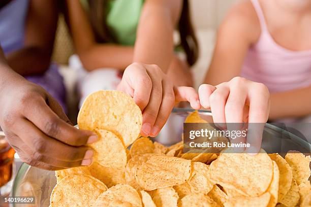 usa, california, los angeles, three girls (10-11) reaching for crisps - crisps stockfoto's en -beelden