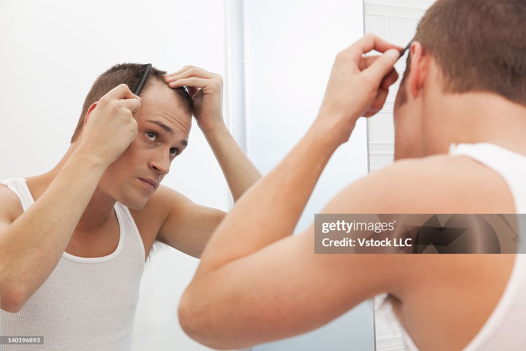 USA, Illinois, Metamora, Man combing hair in front of mirror