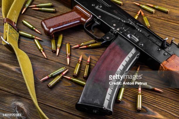 kalashnikov assault rifle and cartridges on wooden background - kalasjnikov stockfoto's en -beelden