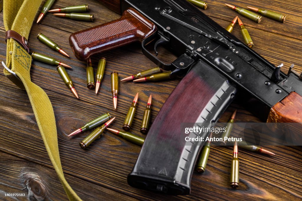 Kalashnikov assault rifle and cartridges on wooden background