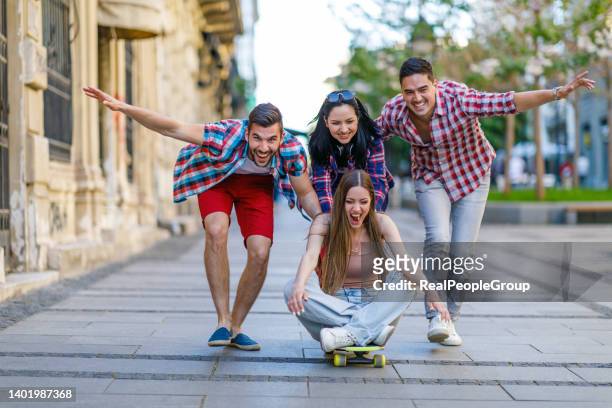 eine gruppe glücklicher menschen hängt zusammen ab und genießt skateboard im freien. - international student day stock-fotos und bilder