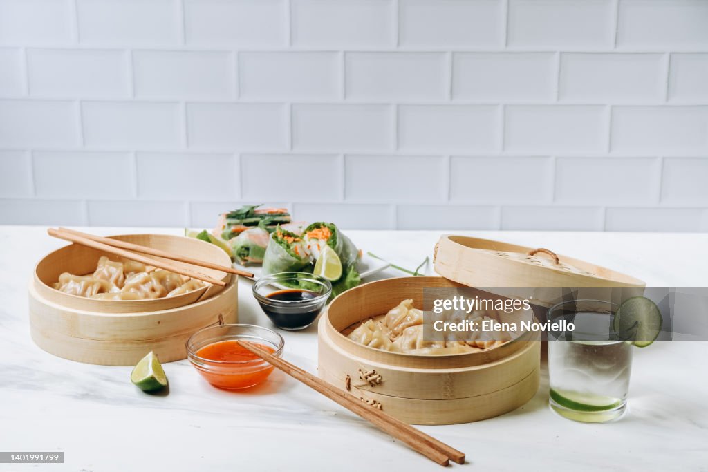 Chinese Korean Japanese food gyoza dumplings in a bamboo steamer and rice paper Vietnam spring rolls with vegetables