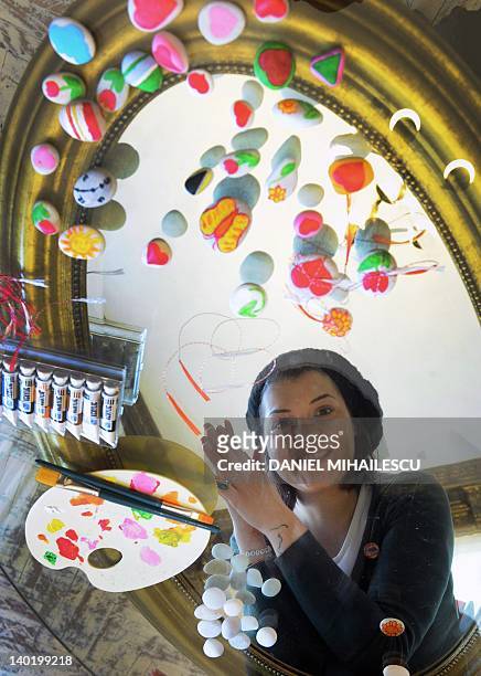 Carmen Miron, a 23 year-old Romanian girl, poses next to her "martisor" creations in Bucharest on February 24, 2012. Every March 1st, parents and...