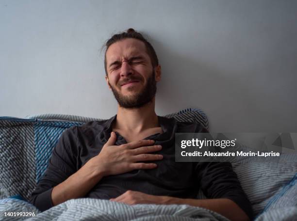 white man inside the bed with chest pain is suffering - pain face portrait stockfoto's en -beelden