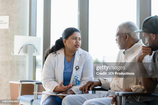 compassionate female doctor discusses medical issues with senior patient - spoedeisende geneeskunde stockfoto's en -beelden