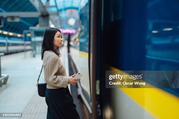 young businesswoman on business trip boarding train at railway station - business women london stock-fotos und bilder