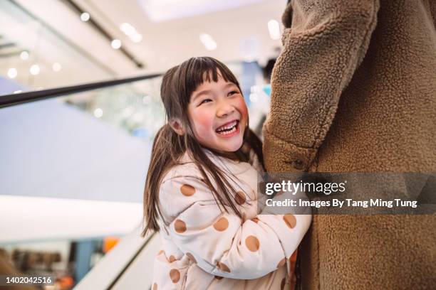 lovely cheerful girl standing in escalator with mom in shopping mall - chinese young adults shopping imagens e fotografias de stock