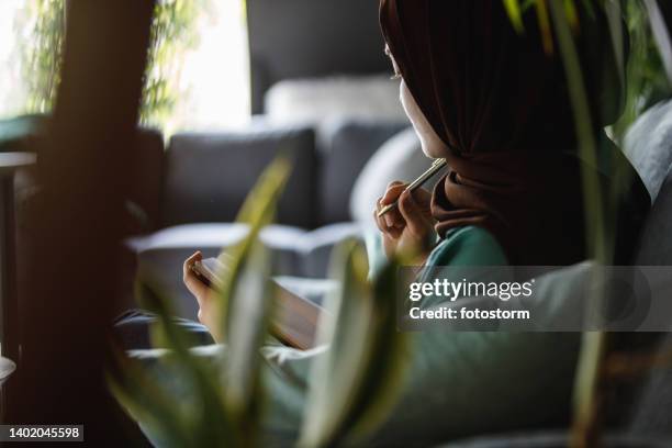 young woman contemplating what to write about in her diary - burka stock pictures, royalty-free photos & images