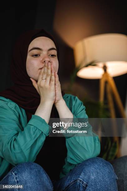 young woman sitting with praying hands in front of face, contemplating - burka stock pictures, royalty-free photos & images