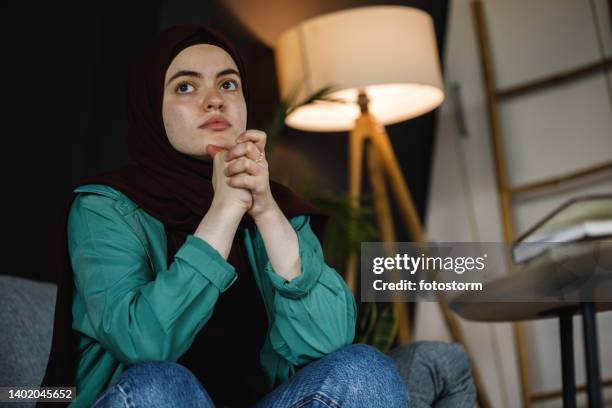 copy space shot of young woman sitting with hands clasped, contemplating, worrying - burka stock pictures, royalty-free photos & images