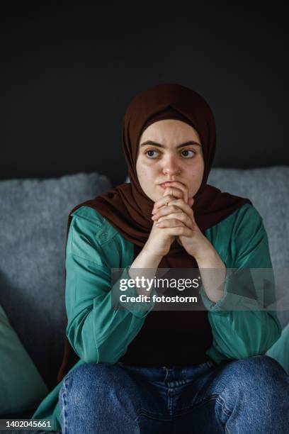 anxious young woman worrying about something, hands clasped in front of face - burka stock pictures, royalty-free photos & images