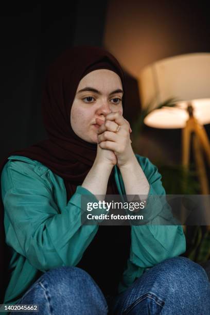 young woman sitting and praying for her problems to go away - burka stock pictures, royalty-free photos & images