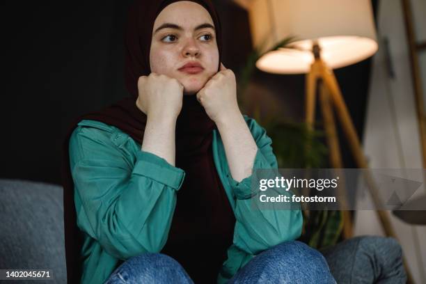 bored young woman sitting with hands under chin, contemplating - burka stock pictures, royalty-free photos & images