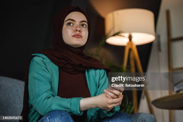 worried young woman cracking her knuckles while contemplating - burka stock pictures, royalty-free photos & images