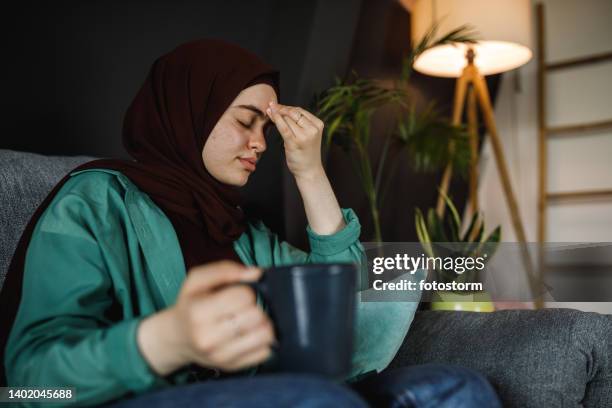 resting on the sofa and having tea while experiencing a headache - burka stock pictures, royalty-free photos & images