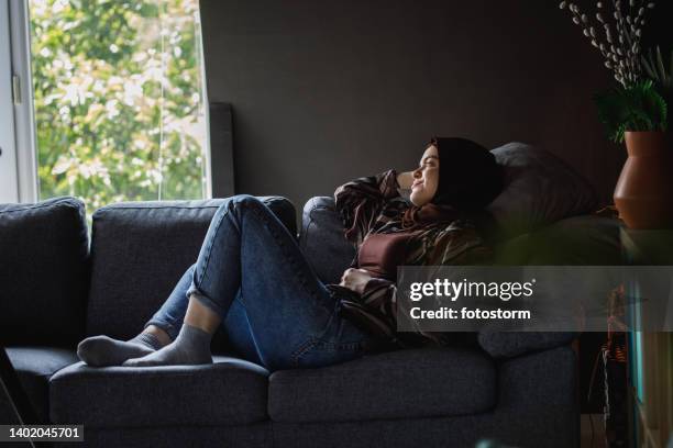 copy space shot of young woman relaxing on the sofa and daydreaming - burka stock pictures, royalty-free photos & images