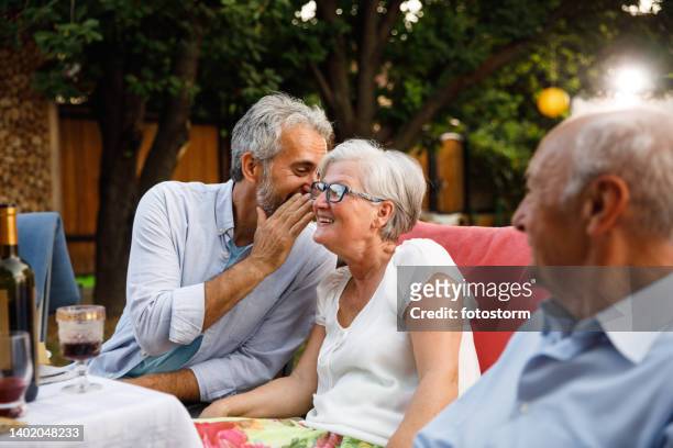 friends whispering and sharing secrets during a dinner party - secret garden party bildbanksfoton och bilder