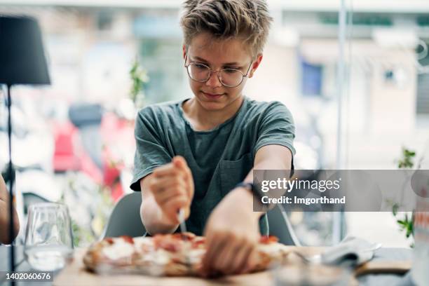 teenage boy enjoying eating a sicilian pizza in restaurant. - trying new food stock pictures, royalty-free photos & images