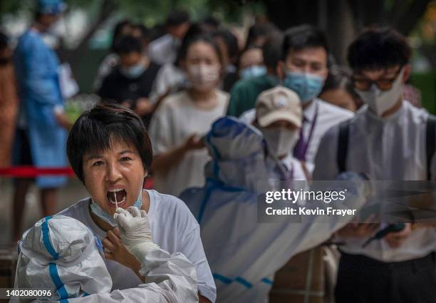 Health worker conducts a nucleic acid test on a woman as others wait in line at a testing site on June 10, 2022 in Beijing, China. China says it has...