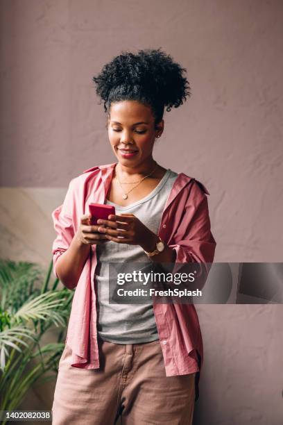 una hermosa y feliz empresaria de raza mixta enviando mensajes de texto en su teléfono inteligente - relief emotion fotografías e imágenes de stock