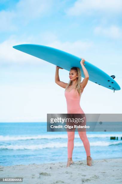 sportive female surfer with surfboard placed on the head on seashore - big wave surfing 個照片及圖片檔