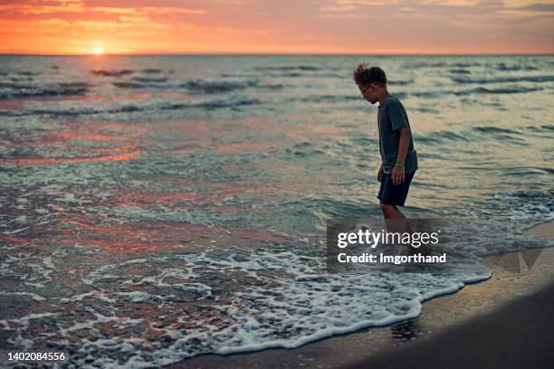 teenage boy playing soccer on on beach - barefoot teen boys stock pictures, royalty-free photos & images