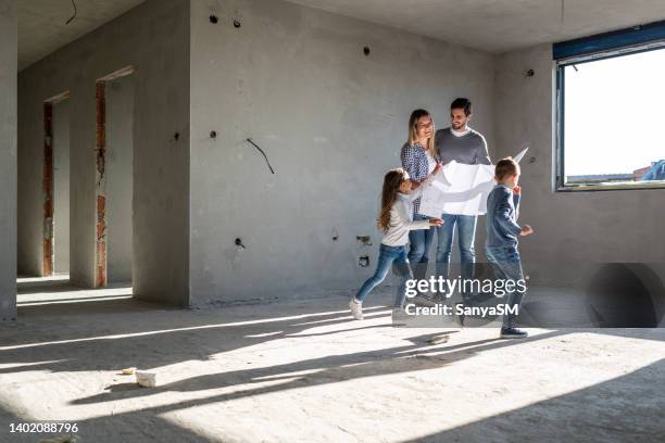 happy family analyzing plans at their new apartment - herbouwen stockfoto's en -beelden