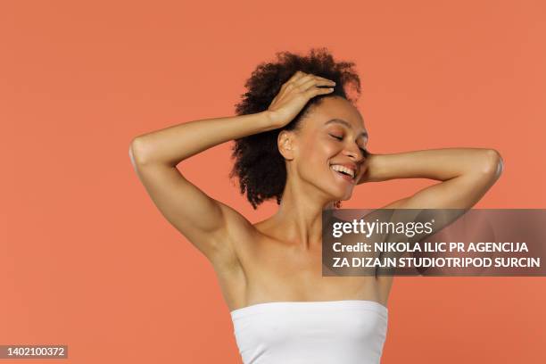 portrait of a beautiful african american woman with curly hair in her 30s posing in  white shirt no make up  stock photo - smooth stock pictures, royalty-free photos & images