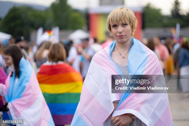 eine geschlechtsspezifische person bei der gay-pride-parade mit einer pansexaul-flagge - bi annual stock-fotos und bilder