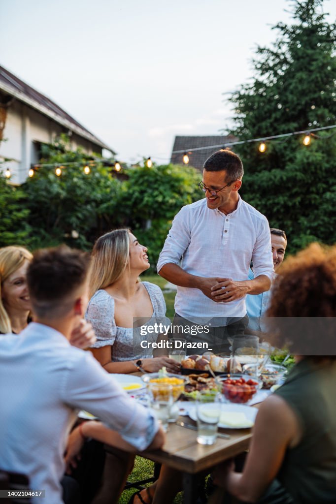 Man having speech during outdoor dinner with friends and family