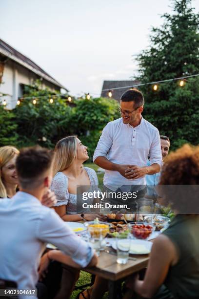 man having speech during outdoor dinner with friends and family - enjoying with friends bildbanksfoton och bilder