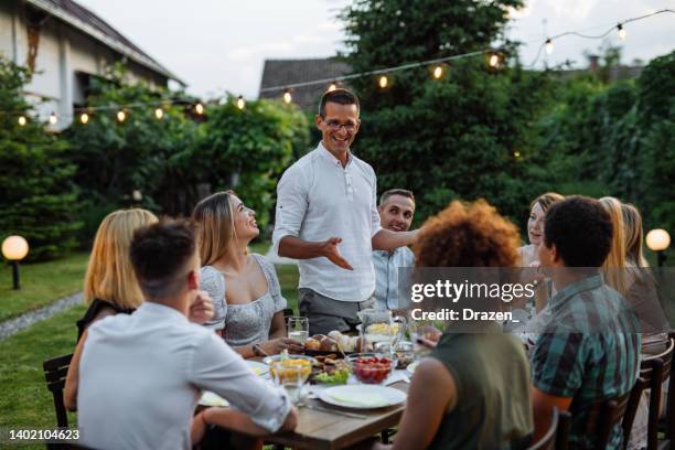 uomo che parla durante la cena all'aperto con amici e familiari - pranzare allaperto foto e immagini stock